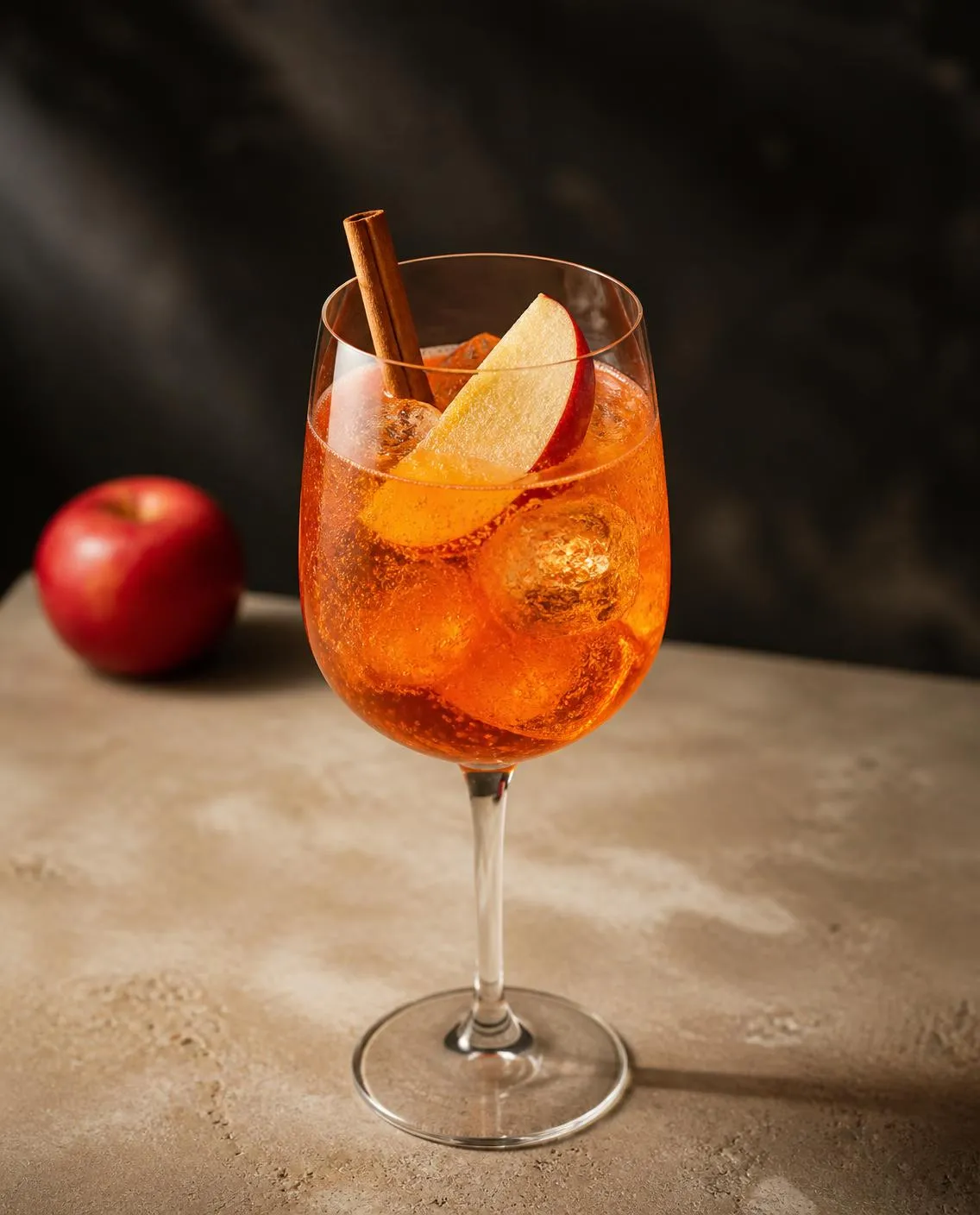 Aperol Apple Cider Spritz in a wine glass with apple slice and cinnamon stick (optional) (AI-generated image)